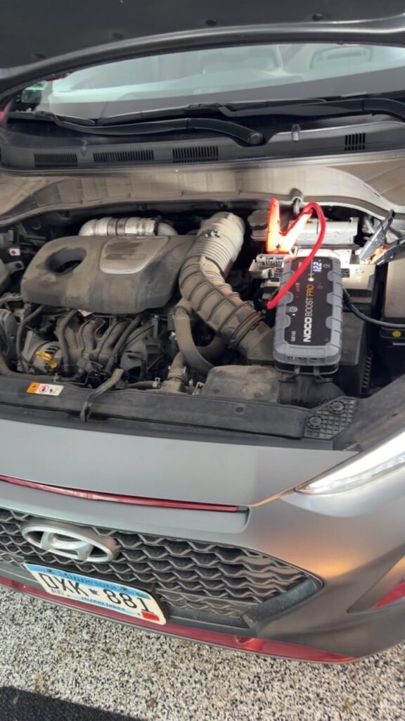 Battery booster connected under a vehicle hood during a Minneapolis jump start